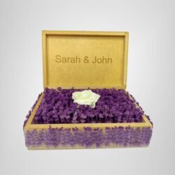 Personalized wooden flower box with "Sarah & John" engraving in Courier New font (2 cm height), filled with vibrant purple real preserved lavender and a single artificial white rose. Ideal for romantic gifts, weddings, anniversaries, or Valentine’s Day celebrations, this handcrafted keepsake box measures 21 cm L x 14 cm W x 7 cm H. The natural wood finish and aromatic lavender scent make it a timeless gift for couples to cherish forever. Crafted with love by Sear Handcrafted Elegance.
