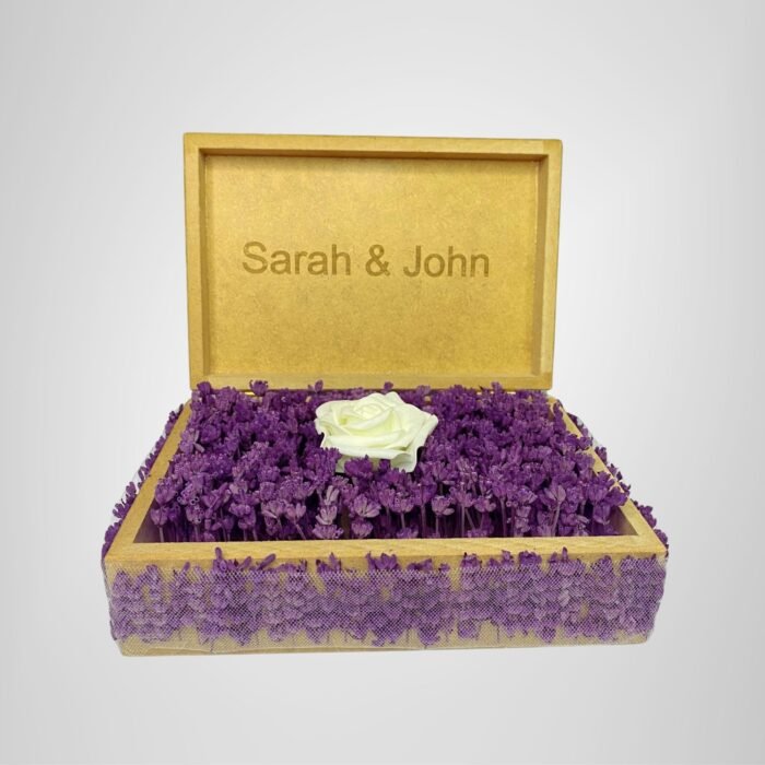 Personalized wooden flower box with "Sarah & John" engraving in Courier New font (2 cm height), filled with vibrant purple real preserved lavender and a single artificial white rose. Ideal for romantic gifts, weddings, anniversaries, or Valentine’s Day celebrations, this handcrafted keepsake box measures 21 cm L x 14 cm W x 7 cm H. The natural wood finish and aromatic lavender scent make it a timeless gift for couples to cherish forever. Crafted with love by Sear Handcrafted Elegance.