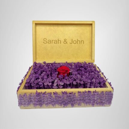 Personalized wooden flower box with "Sarah & John" engraving in Courier New font (2 cm height), filled with vibrant purple real preserved lavender and a single preserved red rose. Ideal for romantic gifts, weddings, anniversaries, birthdays, or special occasions, this handcrafted keepsake box measures 21 cm L x 14 cm W x 7 cm H. The natural wood finish and aromatic lavender make it a timeless gift for couples to cherish forever. Crafted with love by Sear Handcrafted Elegance.