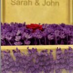 Front view of a personalized wooden flower box engraved with "Sarah & John," filled with purple lavender and a preserved red rose. A stunning romantic gift by Sear Handcrafted Elegance.