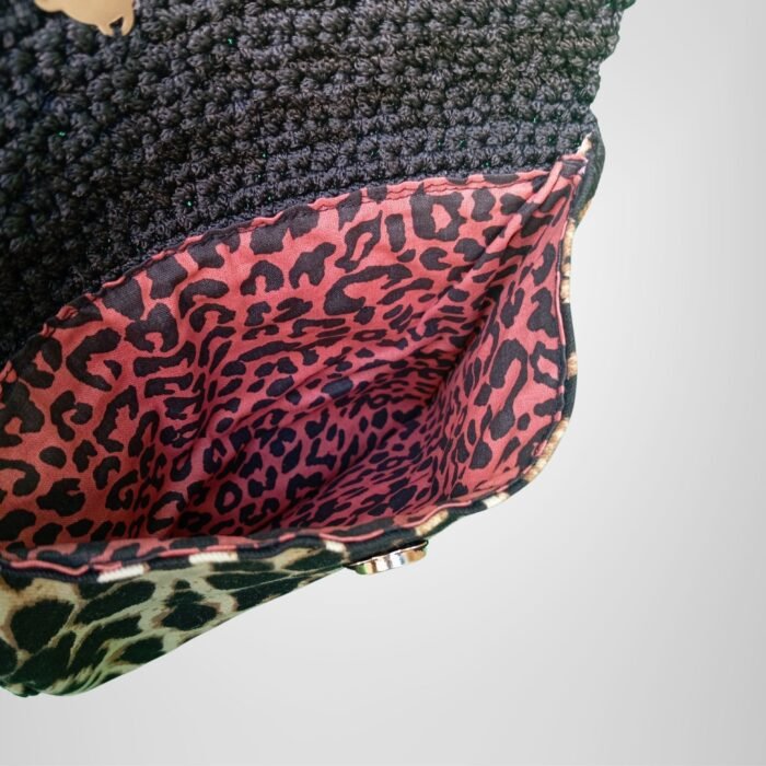 Sear Handcrafted Elegance brand handmade leopard print black crochet clutch bag, inside view. Features a vibrant pink leopard print lining, showcasing elegant craftsmanship and attention to detail.