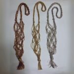 Three Sear Handcrafted Elegance sim macrame wine bottle bags, handmade with shimmering threads, in gold, silver, and red. Each bag features an intricate knot design with a sparkling finish and tassels, displayed flat against a plain background.