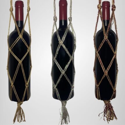 A Sear Handcrafted Elegance sim macrame wine bottle bag, handmade with shimmering threads, displayed in three colors: gold, silver, and red. Each bag holds a wine bottle, showcasing intricate knot designs with a sparkling finish and tassels, against a plain background.