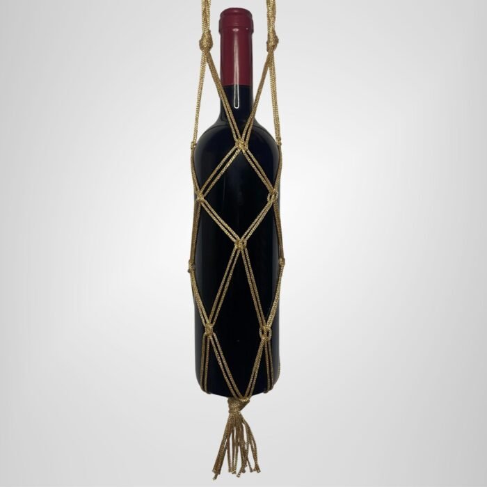 A Sear Handcrafted Elegance sim macrame wine bottle bag in gold, handmade with shimmering threads, holding a wine bottle. The bag features an intricate knot design with a sparkling finish and a tassel at the bottom, displayed against a plain background.
