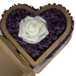 Close-up of an artificial white rose and real lavender flowers in a heart-shaped wooden box, highlighting delicate details and natural beauty.