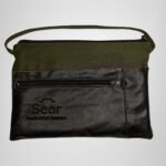 Green and black leather handbag with front pocket detail, modern design. Features the Sear Handcrafted Elegance logo.