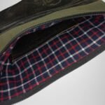 Interior view of a green and black leather handbag by Sear Handcrafted Elegance, featuring a red and blue plaid lining and spacious compartment.