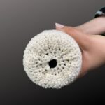 Bottom view of a handmade beige crochet wine bottle bag, highlighting the open-knit pattern and certified organic cotton material. Designed to securely hold wine or water bottles with a stylish, eco-friendly look.