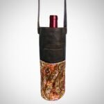 Handmade leather paisley wine bag with leather strap by Sear Handcrafted Elegance, holding a wine bottle.